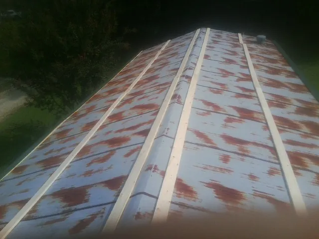 Rusted metal roof panels with new wood purlins before replacement — Storm Damage Roof Repair in North Lawrence by Roofing Brothers