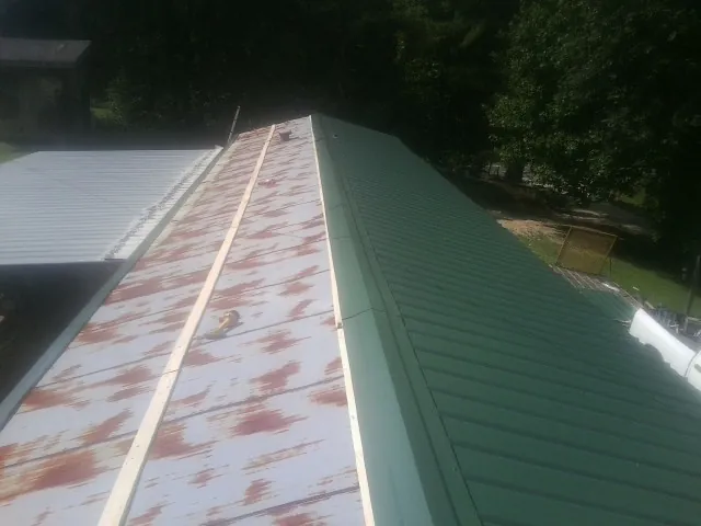 Old rusted panels beside newly installed green metal roofing — Wind Damage Roof Repair by Roofing Brothers in North Lawrence