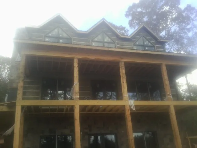 Dormers and porch framing on a large log home under construction — Roof Coating work by our crew in North Lawrence