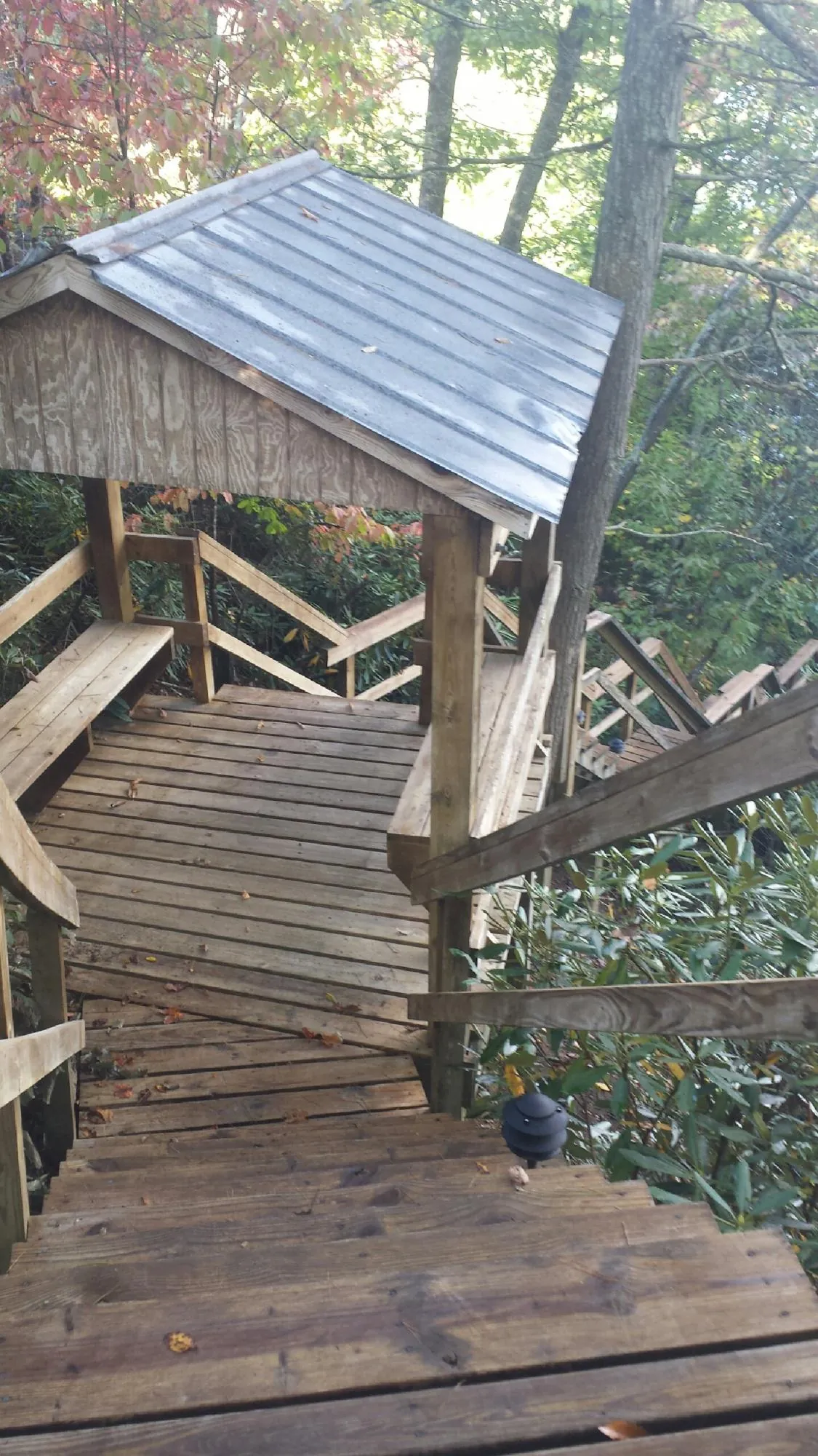 Metal roofed shelter over wooden steps on a wooded walkway — Skylight Repair & Installation work by our crew in North Lawrence