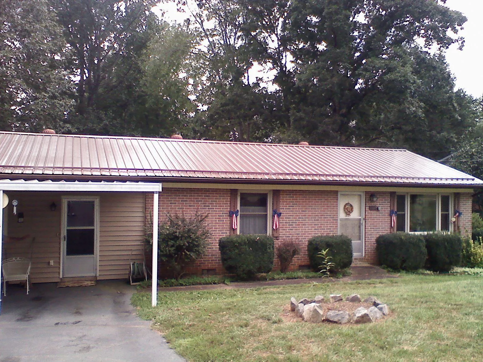 Bronze metal roof and carport on a brick ranch home — Roof Repair work by our crew in North Lawrence