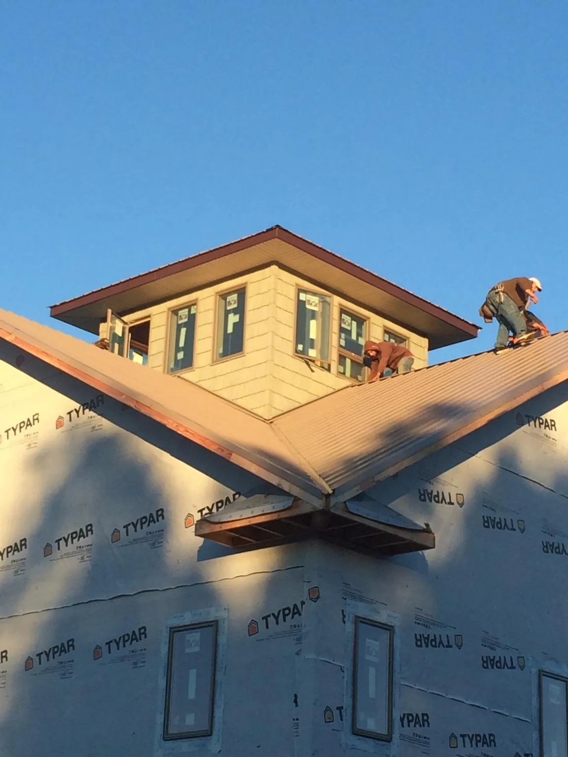 Roofers working around a rooftop cupola on a new metal roof at sunset — Roof Waterproofing in North Lawrence by Roofing Brothers